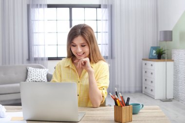 Ev ofis masasında laptop ile çalışan genç kadın