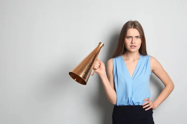 Jovem mulher com megafone no fundo claro — Fotografia de Stock