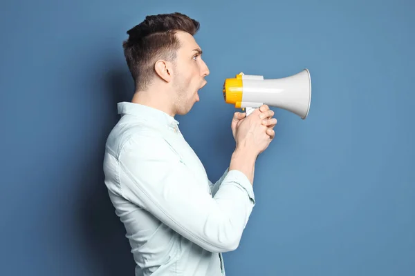 Jovem gritando em megafone sobre fundo de cor — Fotografia de Stock