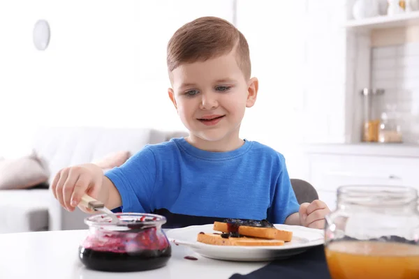 可爱的小男孩在餐桌上洒上甜甜果酱 — 图库照片