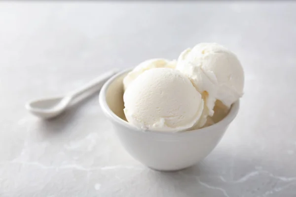 Tigela com saboroso sorvete de baunilha no fundo claro — Fotografia de Stock