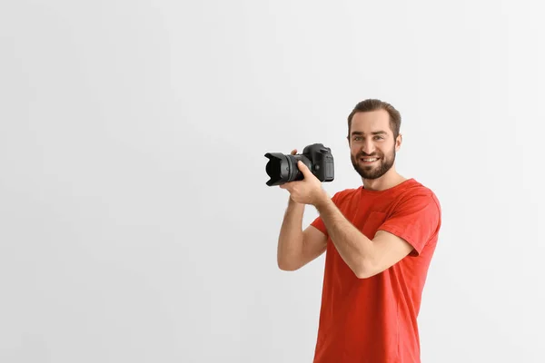 Joven fotógrafo con cámara profesional sobre fondo blanco —  Fotos de Stock