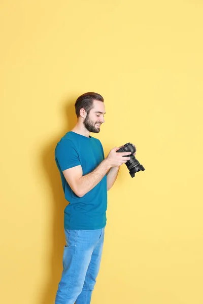 Junger Fotograf mit professioneller Kamera auf farbigem Hintergrund — Stockfoto