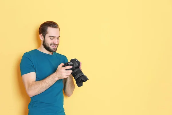Jovem fotógrafo com câmera profissional em fundo de cor — Fotografia de Stock