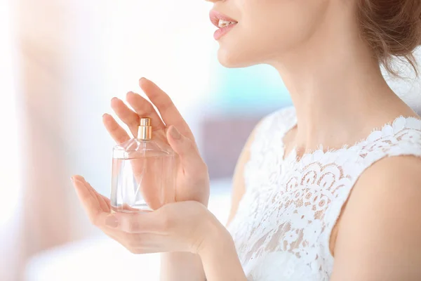 Piękna młoda kobieta z butelki perfum pomieszczeniu, zbliżenie — Zdjęcie stockowe