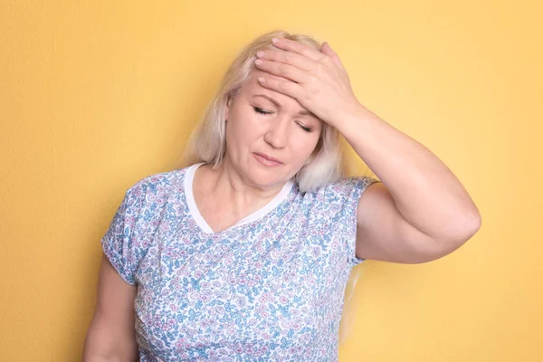 Olgun kadın renk arka plan üzerinde baş ağrısı muzdarip — Stok fotoğraf