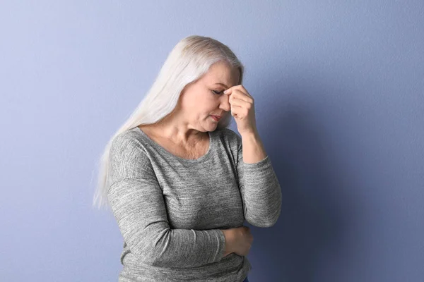Olgun kadın renk arka plan üzerinde baş ağrısı muzdarip — Stok fotoğraf