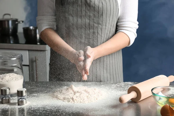 Mujer rociando harina sobre la mesa en la cocina —  Fotos de Stock