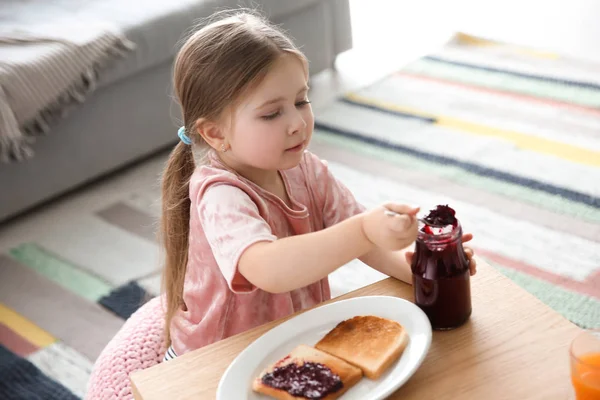Little girl with jam and toasts in living room