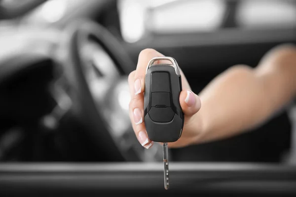 Mujer joven con llave sentada en el asiento del conductor del coche nuevo, primer plano —  Fotos de Stock