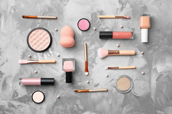 Flache Komposition mit Kosmetikprodukten und Make-up-Pinseln auf grauem Hintergrund — Stockfoto