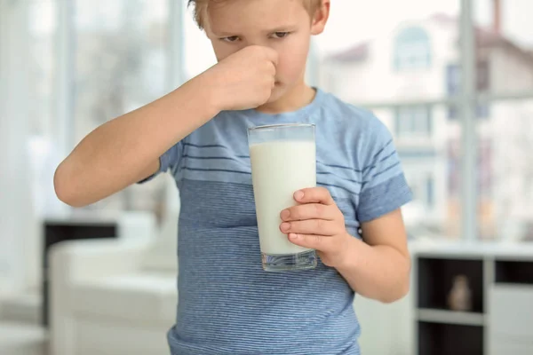Little boy with dairy allergy holding glass of milk indoors — Stock Photo, Image