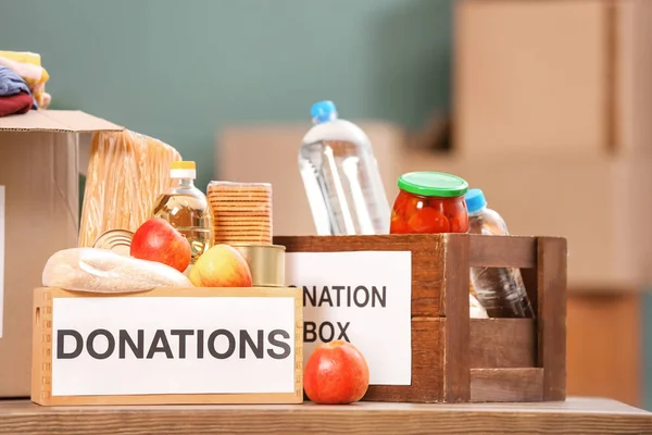 Donation boxes with food products on table indoors