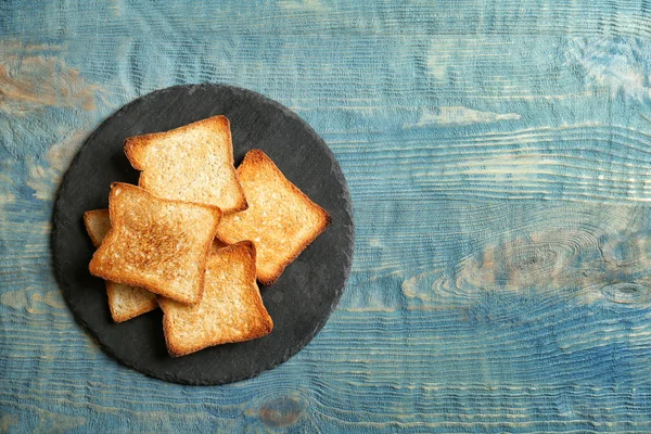 Slate plate with toasted bread on wooden background, top view — Stock Photo, Image