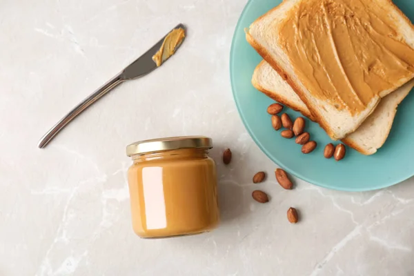 Flat lay composition with peanut butter and toasts on grey background