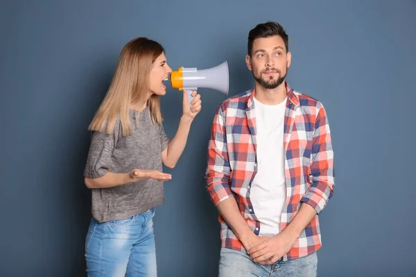 Jonge vrouw met megafoon schreeuwen naar man op kleur achtergrond — Stockfoto