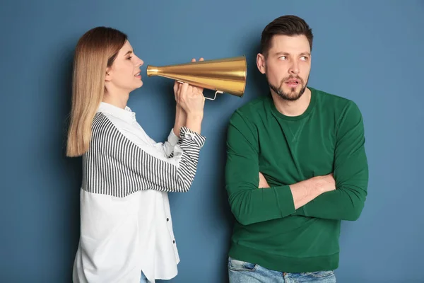 Jonge vrouw met megafoon schreeuwen naar man op kleur achtergrond — Stockfoto