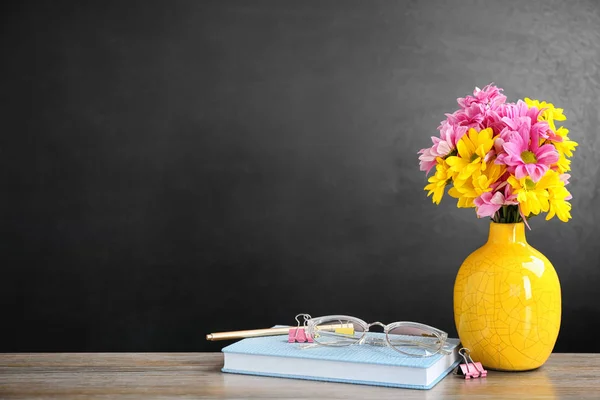 Kytice květin a poznámkové bloky s brýlemi na stole. Oslava dne učitelů — Stock fotografie