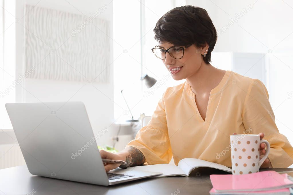 Young woman working with laptop at desk. Home office