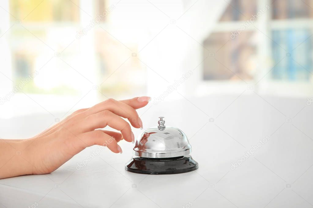 Young woman ringing service bell at reception desk, closeup