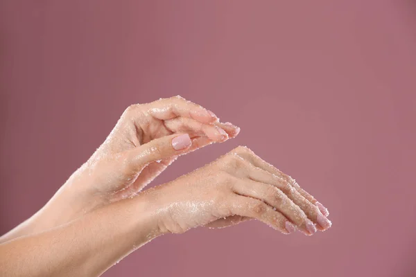 Młoda kobieta, stosując naturalny peeling na dłonie przed kolor tła — Zdjęcie stockowe
