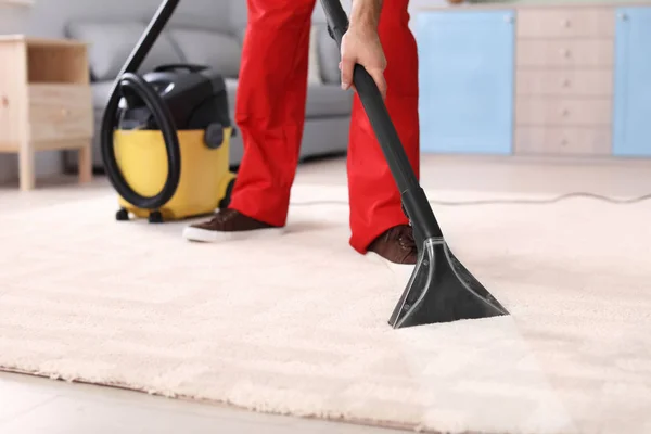 Masculino trabajador limpieza alfombra con vacío en sala de estar —  Fotos de Stock