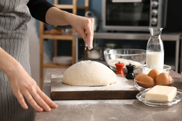 Vrouw beregening meel over deeg op tafel in de keuken — Stockfoto