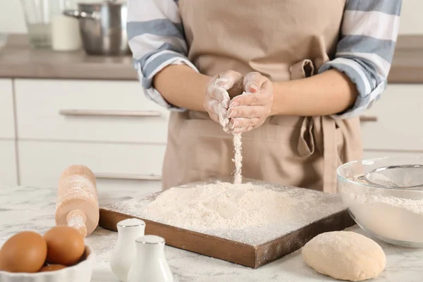 Mujer rociando harina por la borda en la mesa en la cocina —  Fotos de Stock