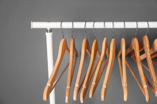 Trilho de roupas com cabides de madeira no fundo cinza — Fotografia de Stock
