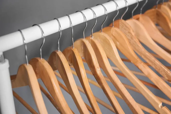 Trilho de roupas com cabides de madeira no fundo cinza — Fotografia de Stock