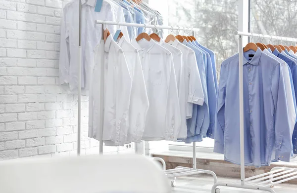 Rastrelliere con vestiti puliti su appendini dopo lavaggio a secco all'interno — Foto Stock