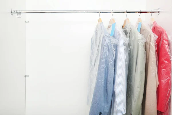 Scaffale con vestiti puliti dopo lavaggio a secco su appendini nell'armadio — Foto Stock