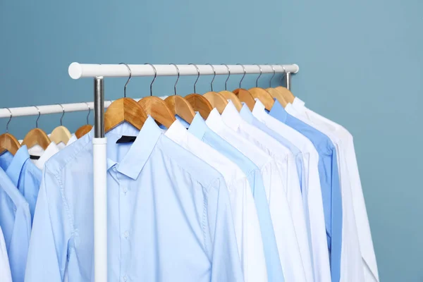 Bastidores con ropa limpia después de la limpieza en seco contra el fondo de color — Foto de Stock