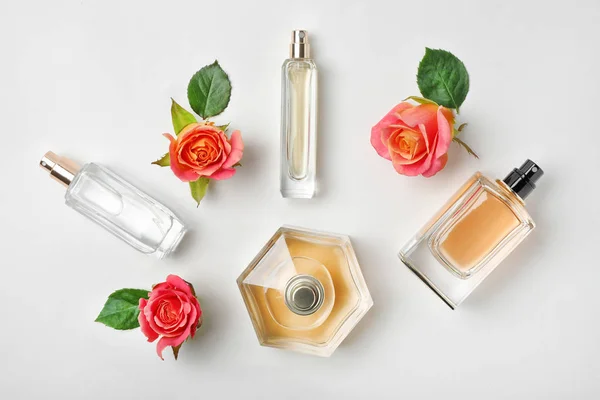 Composición con frascos transparentes de perfume y hermosas flores sobre fondo blanco —  Fotos de Stock