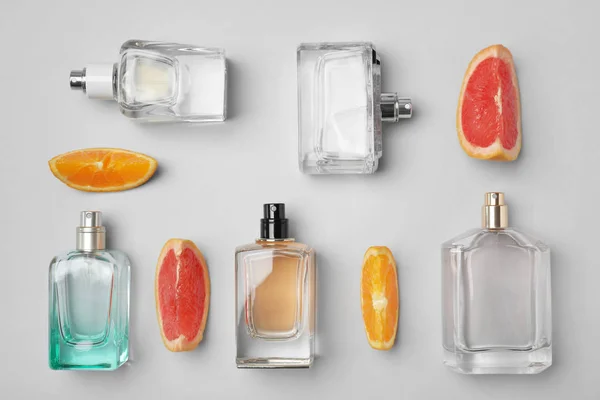 Mieszkanie świeckich skład butelek perfum i owoców cytrusowych, na jasnym tle — Zdjęcie stockowe