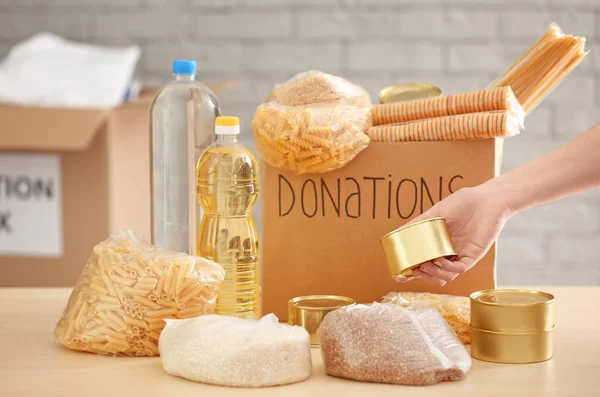 Voluntarios recogiendo alimentos en caja de donación en interiores —  Fotos de Stock