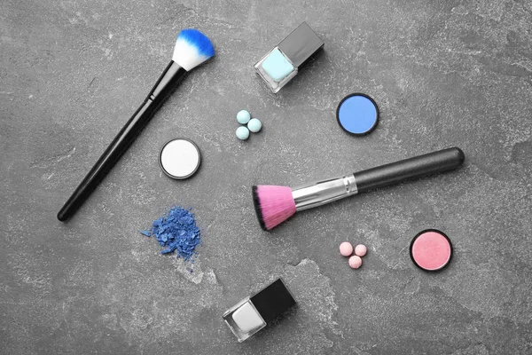 Composición plana con productos cosméticos y pinceles de maquillaje sobre fondo gris — Foto de Stock