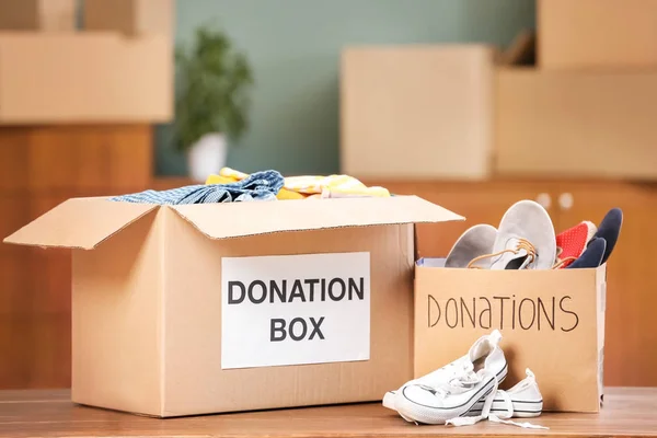 Cajas de donación con ropa y zapatos en la mesa en interiores — Foto de Stock