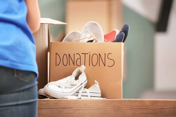 Caja de donación con zapatos en la mesa en el interior — Foto de Stock