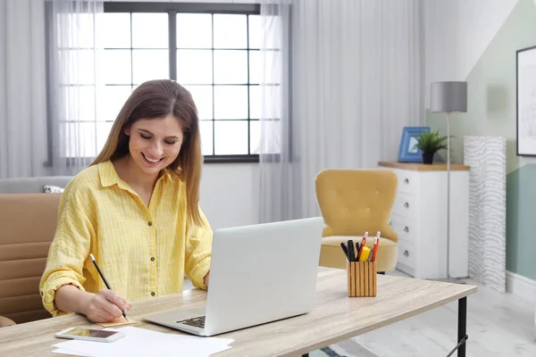 Mladá žena, pracující s přenosným počítačem u přepážky v domácí kanceláři — Stock fotografie