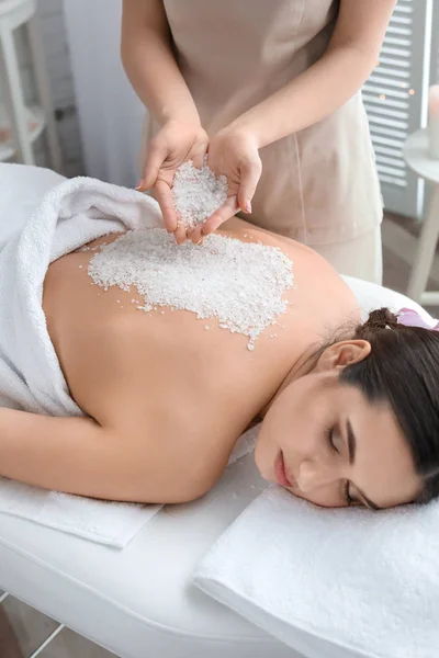 Jeune femme ayant une procédure de nettoyage du corps avec du sel de mer dans un salon de spa — Photo
