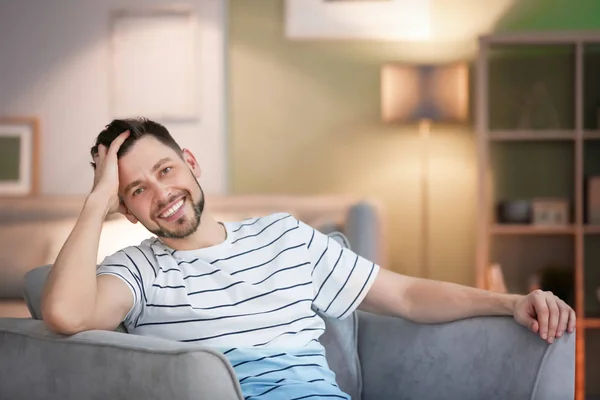 Young man sitting in armchair at home — Stock Photo, Image