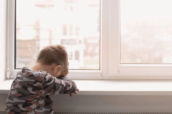 Rapazinho solitário perto da janela dentro de casa. Autismo infantil — Fotografia de Stock