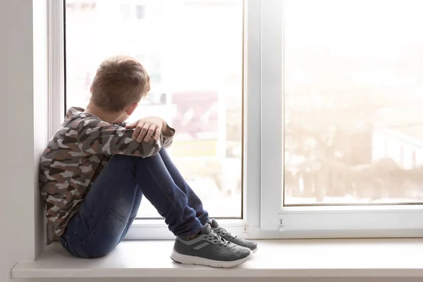 Rapazinho solitário perto da janela dentro de casa. Autismo infantil — Fotografia de Stock