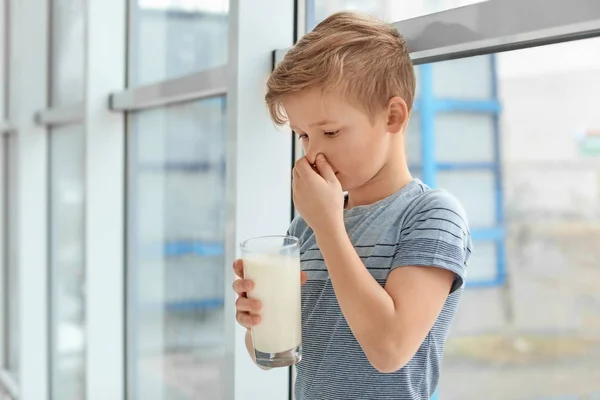 Little boy with dairy allergy holding glass of milk indoors — Stock Photo, Image