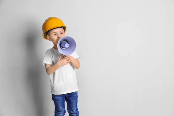 Adorabile bambino in hardhat con megafono su sfondo chiaro — Foto Stock