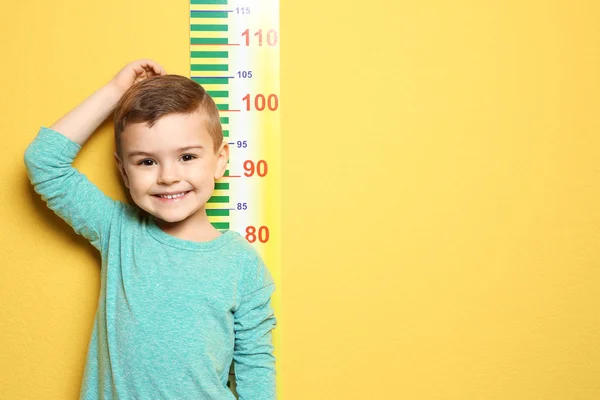 Μικρό αγόρι μέτρηση του ύψους σε χρώμα φόντου — Φωτογραφία Αρχείου