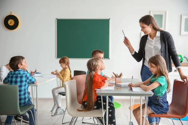 Leuke lieve kinderen met leraar in de klas op school — Stockfoto