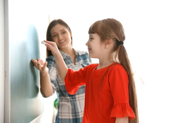 Jonge leraar en meisje in de buurt van schoolbord in de klas — Stockfoto