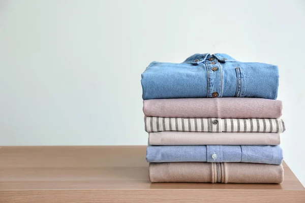 Stack of clothes on table against light background — Stock Photo, Image